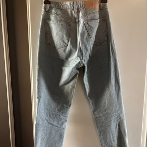 Zara  ljusblå jeans straight fit - Klassiska  jeans i ljusblå denim med raka ben och normal passform. Femficksmodell med knappgylf och tydlig läderpatch bak i midjan. Perfekta för en avslappnad och tidlös stil.