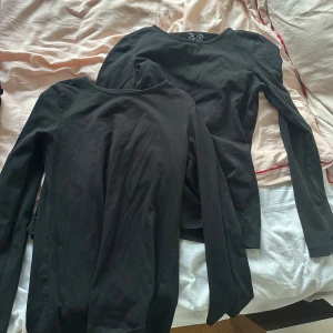 Svarta långärmade tröjor i bomull - Två svarta långärmade tröjor från Lindex i mjuk bomull. Klassisk rund halsringning och enkel, stilren design som funkar till allt. Perfekta basplagg för lager-på-lager eller att bära som de är. Säljes tillsammans. 140 fast passar mig med xs