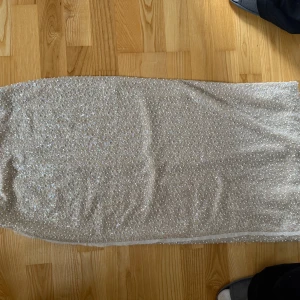 Glittrig champagnefärgad maxikjol från Zara - Säljer en glittrig maxikjol från Zara i champagnefärg med paljetter över hela tyget. Kjolen har en elegant och festlig look, perfekt för speciella tillfällen. Materialet är mjukt och skimrande syntet. HELT NY