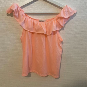 Topp - Säljer en söt topp från H&M med volang längs halsringningen. Perfekt för varma dagar och ger en somrig känsla. Tunn och mjuk bomullskvalitet.