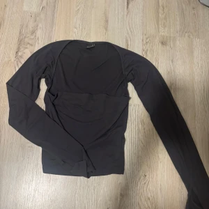 Svart långärmad topp - En stilren svart långärmad topp med rund halsringning. Tunn och mjuk i materialet, perfekt att matcha med jeans eller kjol. Enkel design utan synliga detaljer. Mörk grå