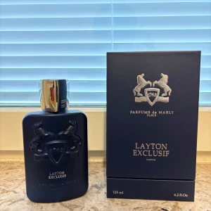 Layton Exclusif Parfym från Parfums de Marly - Lyxig parfymflaska i mörkblått med silverfärgad kork och elegant reliefmönster av två hästar. Kommer i matchande mörkblå kartong med guldiga detaljer. Doften är exklusiv och passar dig som vill sticka ut.