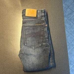 Mörkblå skinny jeans från Nudie Jeans - Snygga mörkblå jeans från Nudie Jeans med klassisk femficksdesign och läderpatch bak. Modellen är skinny med smal passform och normal midja. Jeansen har diskreta slitningar och är i stretchigt denimtyg för extra komfort.