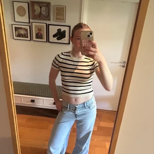 Randig t-shirt från Gina Tricot - Säljer en t-shirt från Gina Tricot med svarta och vita horisontella ränder. T-shirten har tight passform och korta ärmar. Perfekt till jeans eller kjol för en enkel och snygg look.