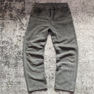 Grå jeans, Loose/baggy fit - Säljer ett par grå jeans med rak och lös passform . Byxorna har dragkedja och knapp i midjan samt bälteshällor. Perfekta för en avslappnad och stilren look.