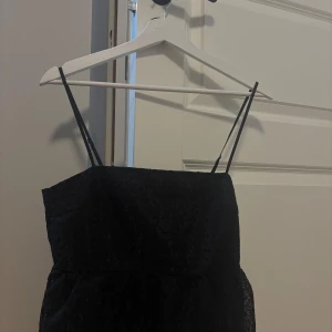 Svart topp från H&M - Säljer en svart topp från H&M med tunna axelband och vacker spetsdetalj.🥰🥰