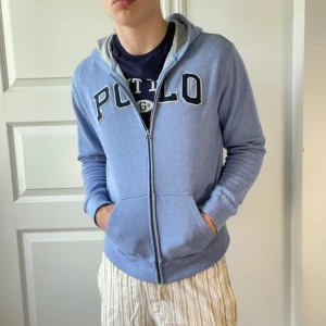 Polo zip up - Ljusblå zip up med Polo märke. Väldigt bra skick. Sitter väldigt bra. Modellen är 178, 74 kg. Xl i barn Strlk = M/S i herr