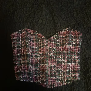 Färgglad korsett-topp från Zara - Säljer en snygg korsett-topp från Zara i storlek S. Toppen har ett rutigt mönster i rosa, vitt, svart och grönt med struktur och en croppad passform. Perfekt för att lyfta vilken outfit som helst!