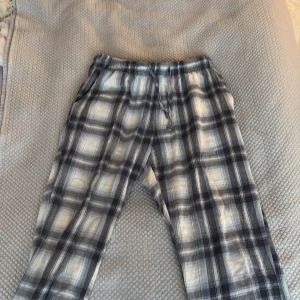 Rutig pyjamasbyxa i svart och vitt - Mysiga pyjamasbyxor i svartvitt rutigt mönster med resår i midjan och avslappnad passform. Perfekta för hemmakvällar eller lata morgnar. Tunt och mjukt material som känns skönt mot huden.