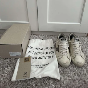  sneakers från Golden Goose - Säljer ett par beige sneakers från Golden Goose med vit sula och svart stjärndetalj på sidan. Skorna har snörning och klassisk rund tå. medföljer originalpåse och kartong och kvitto
