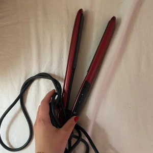 Röd plattång från Remington Silk - Säljer en röd och svart plattång från Remington Silk. Plattången har slimmad design och keramiska plattor för enkel styling. Perfekt för att skapa rakt hår eller mjuka vågor. Lång sladd för smidig användning.