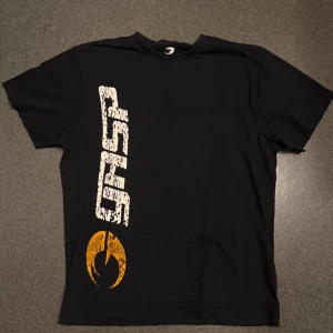 Svart t-shirt från GASP med tryck - Svart t-shirt från GASP med stort vitt och gult tryck både fram och bak. T-shirten har en klassisk passform och är perfekt för dig som gillar gym plagg.