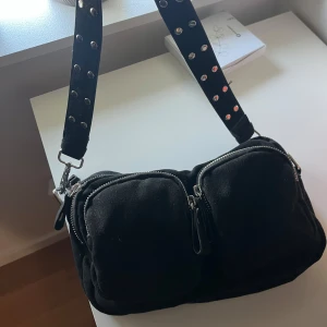 Gina tricot väska  - Cool svart axelväska med bred axelrem dekorerad med silvriga nitar. Väskan har två stora fack framtill med dragkedjor och är perfekt för att bära med sig det viktigaste.❣️