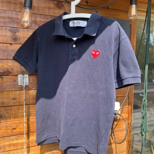 CDG Play Piké - En Comme Des Garcon Play piké i storlek M. Plagget är i bra skick men aningen lite solblekt. Känn dig fri att fråga om du undrar något!