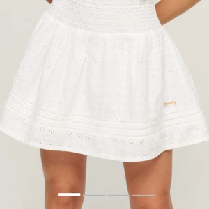 Vit broderad kjol från Superdry - Söt vit kjol från Superdry med broderade detaljer och resår i midjan. Kjolen har ett romantiskt hålmönster och är lätt utställd. Perfekt för varma dagar och ger en fräsch look.