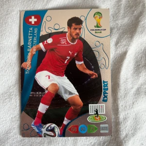 Röd Schweiz Barnetta kort Vm2014 - Röd Schweiz landslagströja från Puma med vitt tryck och nummer 7 på bröstet. Tröjan har vita detaljer vid ärmslut och krage samt Schweiz flagga på bröstet. Perfekt för fotbollsfans!