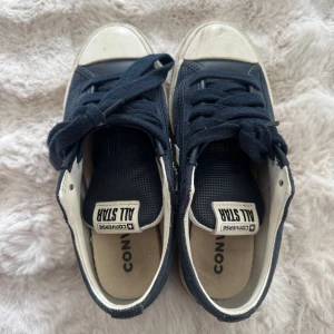 Star Player 76 Unisex - Mörkblå Converse All Star sneakers med vita detaljer och snörning. 