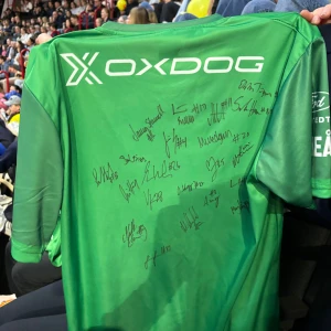 Grön matchtröja från Oxdog med autografer - Säljer en grön matchtröja från Oxdog med flera autografer på framsidan. Tröjan har korta ärmar och är täckt av olika sponsorloggor på baksidan. Perfekt för dig som gillar innebandy och vill ha ett unikt samlarobjekt.