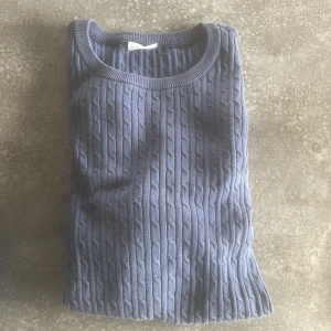 Blå kabelstickad tröja från John Henric - Säljer en blå kabelstickad tröja från John Henric i storlek M. Tröjan har rund halsringning och långa ärmar, perfekt för lager-på-lager. Klassisk och stilren design som passar till många tillfällen.