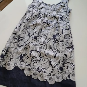 Blommig silkesklänning från See by Chloé - Supersnygg blommig klänning från See by Chloé i 100% silke. Klänningen har svartvitt mönster, knappar framtill och markerad midja. Perfekt för dig som vill sticka ut med en unik och lyxig look.