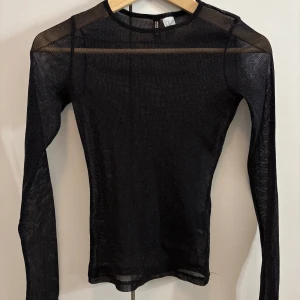 Svart glittrig mesh-top från H&M - Säljer en svart långärmad mesh-top från H&M med glittriga detaljer. Storlek XS men sitter lagom som en S för den är något större i storlek.