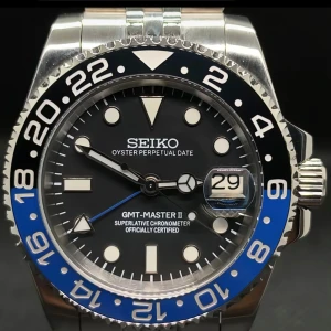 Seiko GMT-Master II klocka med blå och svart bezel - Stilren Seiko GMT-Master II med svart urtavla, blå och svart vridbar bezel samt datumfönster. Klockan har silverfärgat armband i rostfritt stål och tydliga indexmarkeringar. Perfekt accessoar för dig som gillar klassisk design.