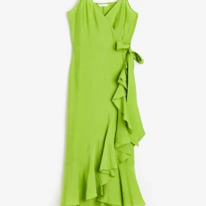 Vadlång grön klänning med volangkant - Vadlång i vävd kvalitet, de smala axelbanden är reglerbara💚 Klänningen har omlott fram med djup v-ringning som har en dold hyska och hake, breda knytskärp i midjan så du kan dra åt hur du vill! Den är ofodrad och har en volangkant nertill på klänningen, jätte fin på! Prislappen är ej kvar men endast provad inomhus💚