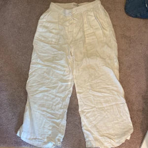 Vita linnebyxor med dragsko - Säljer ett par vita linnebyxor med avslappnad passform och dragsko i midjan. Byxorna är raka i modellen och perfekta för varma dagar. Lätta och luftiga, passar till många olika stilar.