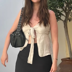 Knyt-top från Gina Tricot - Säljer en stilren knyt-top från Gina Tricot i storlek 38. Toppen har en vacker design med en knytning i fronten som ger en feminin och trendig look. Den är perfekt för sommarens fester eller en avslappnad dag i stan. Kombinera med kjol eller jeans för en komplett outfit! Nästan ny, använd en gång. Ingen synlig slitage.