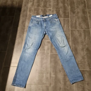Replay Anbass Hyperflex jeans slim fit - Säljer ett par ljusblå Replay Anbass Hyperflex jeans i slim fit. Klassisk femficksmodell med dragkedjegylf och snygga detaljer på bakfickorna. Stretchigt material som ger extra komfort och rörelsefrihet.