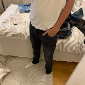 Svarta jeansbyxor från Nudie Jeans Grim Tim - Säljer ett par svarta jeansbyxor från Nudie Jeans i storlek 32/32. Klassisk femficksmodell med normal passform och raka ben. Perfekta till vardags och lätta att matcha med olika outfits.