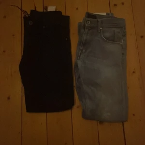 Svarta och ljusblå jeansbyxor - Två par jeansbyxor, ett par svarta och ett par ljusblå. Båda har klassisk femficksdesign och raka ben. Perfekta för en avslappnad stil och passar till det mesta i garderoben.
