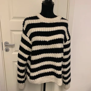 Randig stickad tröja från H&M - Säljer en chunky stickad tröja från H&M med breda svarta och vita ränder. Tröjan har lång ärm, rund halsringning och en oversized passform. Perfekt för kyliga dagar när du vill vara både bekväm och snygg.