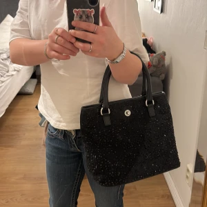 Svart strass handväska från Karen Millen - Säljer en  glittrig handväska med strasstenar från Karen Millen. Den har leopard mönster inuti. Den är perfekt storlek inte för stor eller för liten. Går att ha till fest eller vardags. Den är skit snygg, säljer pågrund av att jag har jätte många väskor redan. Den har inga fläckar eller hål.