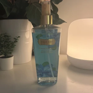 Aqua Kiss Body Mist från Victoria's Secret - Fräsch body mist i blå flaska med guldigt spraymunstycke från Victoria's Secret. Doften heter Aqua Kiss och har en blommig och fräsch karaktär. Flaskan är dekorerad med blå blommor och rymmer 250 ml.