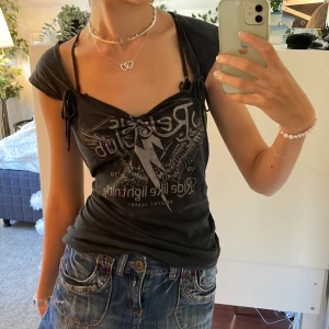 svart topp - svart topp med rosetter och tryck 💗den har några små defekter, den är sliten runt kragen och har två små hål, men inget som märks av när man har på sig den. skriv vid frågor!