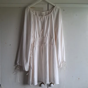 Vit långärmad klänning - Säljer en superfin vit långärmad klänning i storlek S. Klänningen har en lös passform med resår i midjan och vid ärmsluten. Den är perfekt för sommar. Materialet känns lätt och luftigt, vilket gör den bekväm att bära hela dagen. Perfekt för en fest eller en avslappnad dag ute!