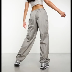 Grå byxor med dragsko - Säljer ett par grå byxor med elastisk midja och dragsko för justerbar passform. Byxorna har en loose fit och är perfekta för en avslappnad stil. Materialet ser ut att vara lätt och bekvämt, vilket gör dem idealiska för vardagsbruk. Storlek S. Köpt från H&M och är slutsåld nu.