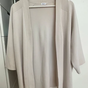 Beige kofta från Filippa K - Säljer en superfin beige kofta i viskos från Filippa K. Den är i storlek S och har en enkel och stilren design. Koftan är trekvartsärmad. Perfekt för både vardag och lite finare tillfällen. Passar bra till höst och vår!