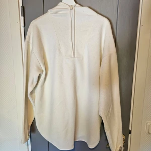 Vit fleece hoodie från 157 - Säljer en supermysig vit fleece hoodie från lager157. Den har en dragkedja framtill och en skön huva. knappt använd. har även tumm-hål vid hand hålen