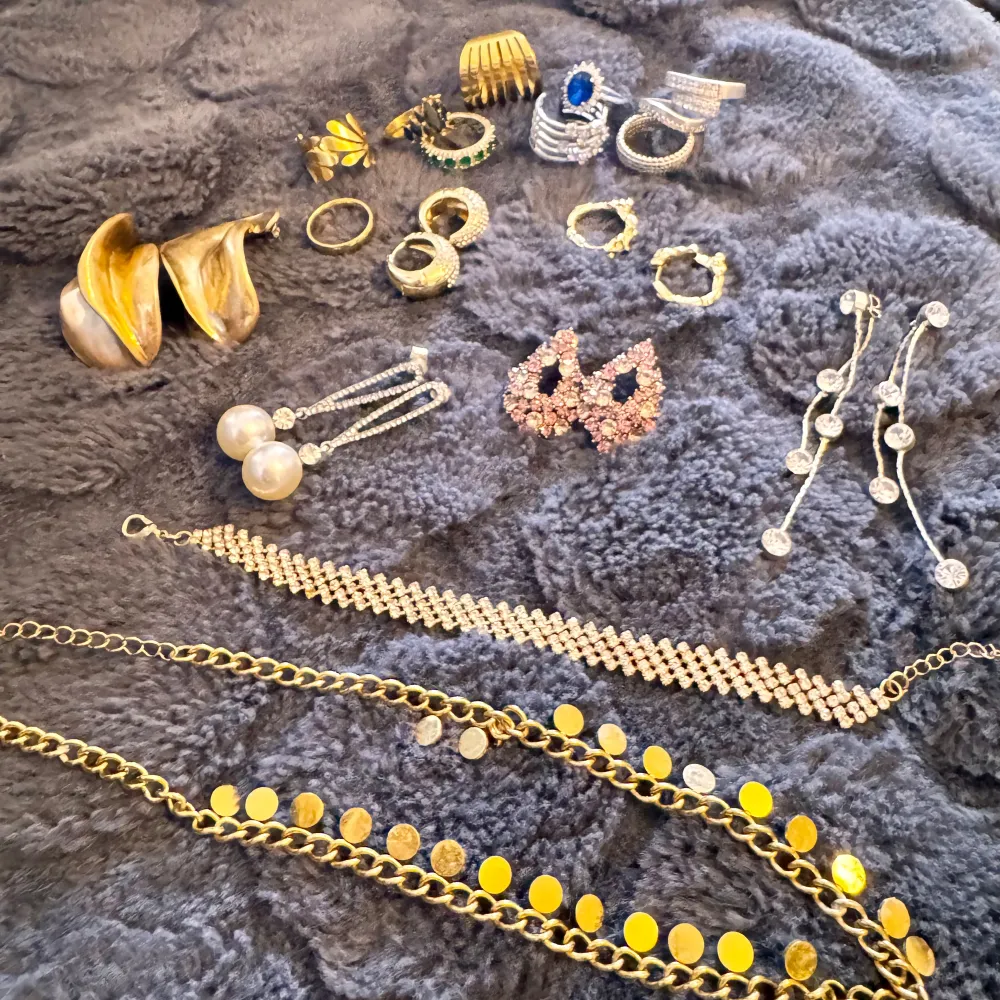 Säljer en samling av smycken(pilgrim med andra äkta märke) som inkluderar flera ringar, örhängen och halsband. Det finns både guld- och silverfärgade smycken, samt några med pärlor och stenar. Perfekt för att piffa upp din outfit oavsett tillfälle! allt är äkta Siler/S.steel/guldplatterat . Asusteet.
