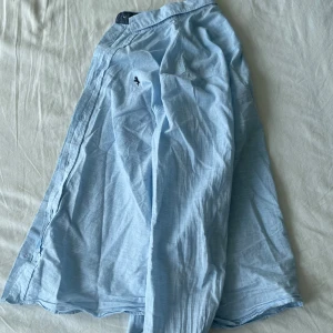 Ljusblå skjorta från H&M - Säljer min favoritskjorta som jag tyvärr växt ur. Skjortan är lljusblå och från H&M. Den är långärmad och är i ett mjukt bomullsmaterial. Den har knappar längs framsidan och en liten broderad detalj på bröstet. Perfekt för både vardag, fest och skolavslutningar! (se sista bild för mini fläck) Frågor? Skriv!