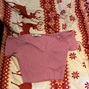 Rosa ribbad offshoulder topp från Zara - Säljer en söt rosa ribbad offshoulder topp från Zara. Perfekt för en trendig look med sin v-ringade design. Passar utmärkt till både jeans och kjol. 💖