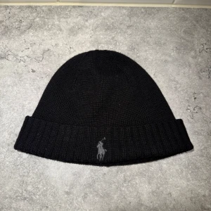 Svart mössa från Polo ralph louren - Snygg svart mössa från Polo Ralph Lauren med broderad logotyp|| mössan är i nyskick och använd vid 1-2 tillfällen|| säljer mössan för så lågt som 300kr.
