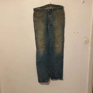 Edwin Blå jeans med slitningar - Säljer ett par klassiska blå jeans med slitningar och en cool vintage-look. De har en rak passform och är utrustade med bälteshällor och fem fickor. Perfekta för en avslappnad stil. JeansStorlek 30waist *34leg