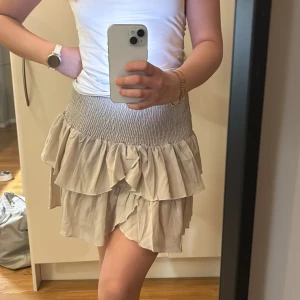 Beige volangkjol från Neo Noir - Säljer en söt beige volangkjol från Neo Noir. Helt ny med prislappen kvar. Nypris 399kr. Storlek M men passar dig med xs-m beroende då midjan är elastisk