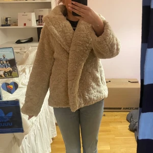Beige ”teddy”jacka - Mysig beige ”teddy”jacka med fluffig textur och stor krage. Perfekt för kyliga dagar när du vill hålla dig varm och stilren. Jackan har en avslappnad passform och är lätt att matcha med olika outfits.