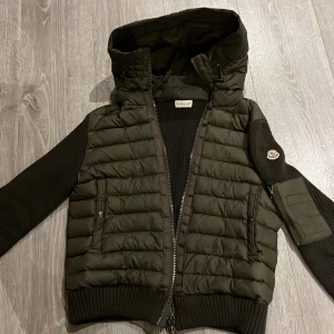 Grön quiltad jacka från Moncler - Snygg grön jacka från Moncler med huva. Jackan har dragkedja och en praktisk ficka på sidan. Hör av er vid minsta fundering.