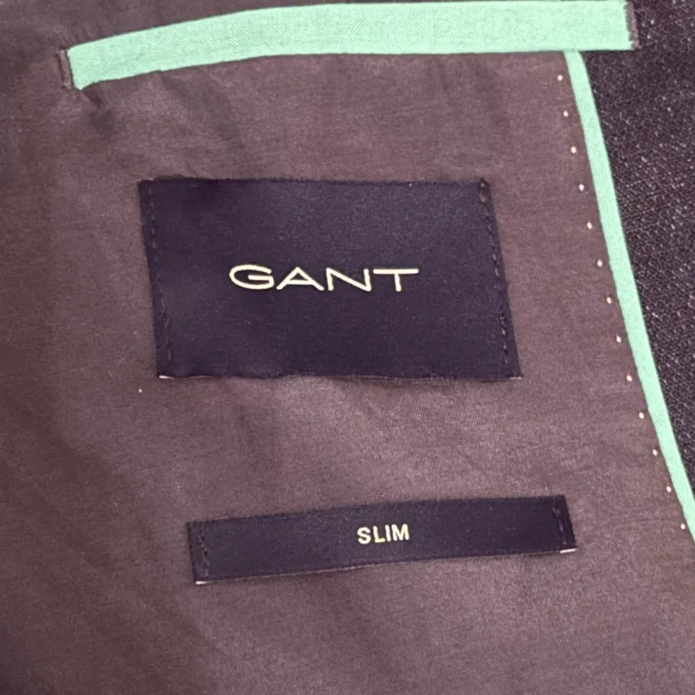Snygg mörkblå kavaj från GANT i slim passform. Kavajen har två knappar framtill och en stilren design. Perfekt för en elegant look. Framkommer ej storlek i kavajen men den passar mig som har M perfekt (har även L i vissa kläder).. Puvut & Bleiserit.