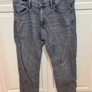 Grå jeans från H&M - Säljer ett par grå jeans från H&M i relaxed fit. De har en klassisk femficksdesign och är tillverkade i bomull. Perfekta för en avslappnad stil.